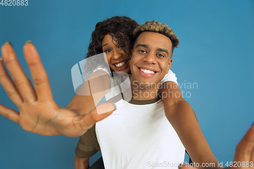 Image of Young emotional african-american man and woman on blue background