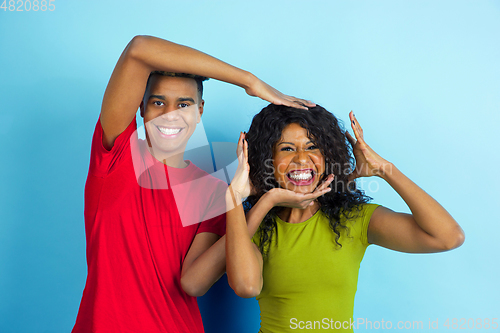 Image of Young emotional african-american man and woman on blue background