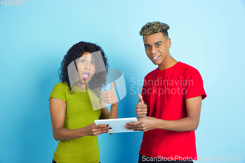 Image of Young emotional african-american man and woman on blue background
