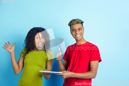 Image of Young emotional african-american man and woman on blue background