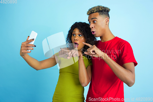 Image of Young emotional african-american man and woman on blue background