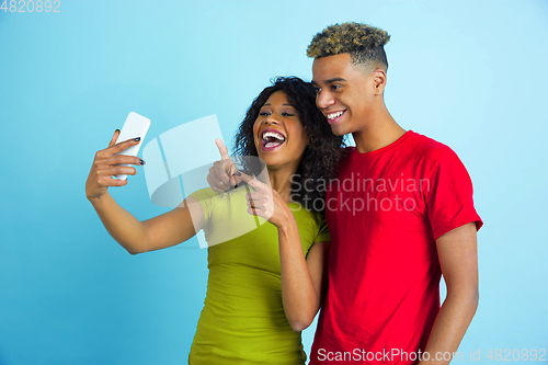 Image of Young emotional african-american man and woman on blue background
