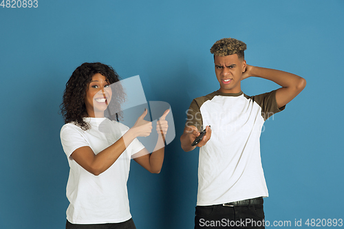 Image of Young emotional african-american man and woman on blue background