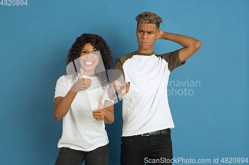 Image of Young emotional african-american man and woman on blue background