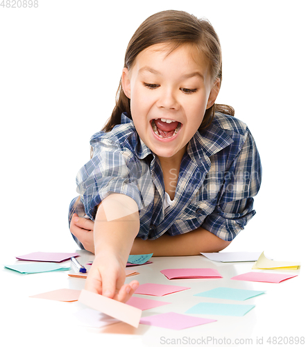 Image of Girl is writing on color stickers using pen