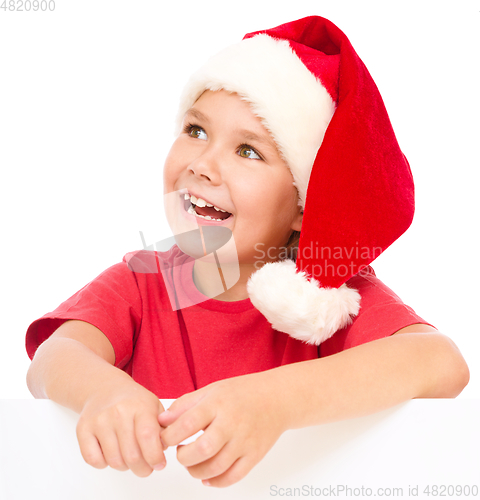 Image of Little girl in santa hat is holding blank board