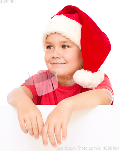 Image of Little girl in santa hat is holding blank board