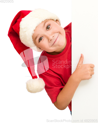 Image of Little girl in santa hat is holding blank board