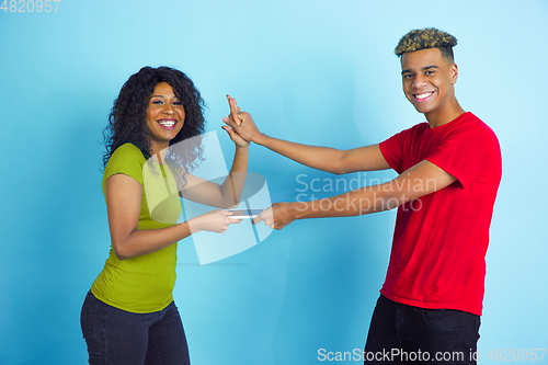 Image of Young emotional african-american man and woman on blue background