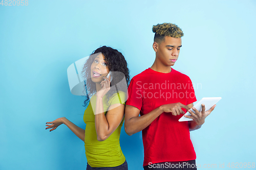Image of Young emotional african-american man and woman on blue background