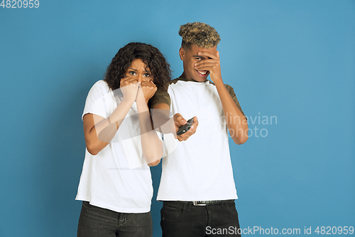 Image of Young emotional african-american man and woman on blue background