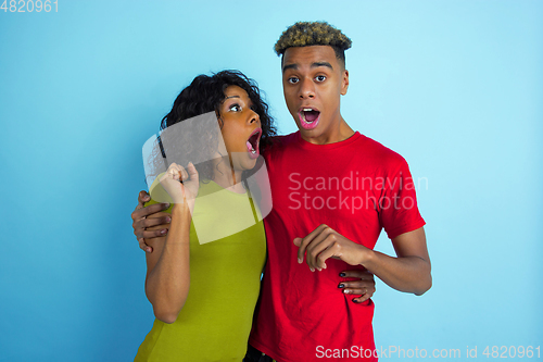 Image of Young emotional african-american man and woman on blue background