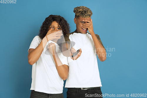 Image of Young emotional african-american man and woman on blue background