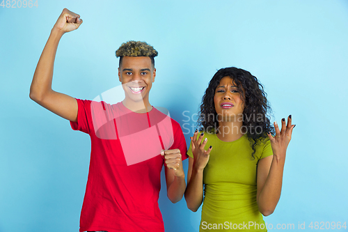 Image of Young emotional african-american man and woman on blue background