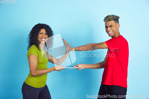 Image of Young emotional african-american man and woman on blue background