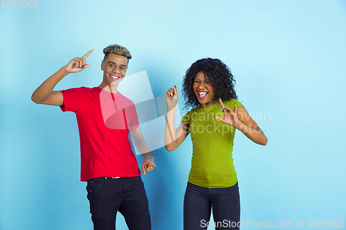 Image of Young emotional african-american man and woman on blue background