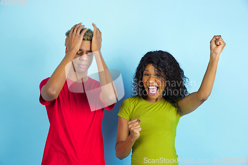 Image of Young emotional african-american man and woman on blue background