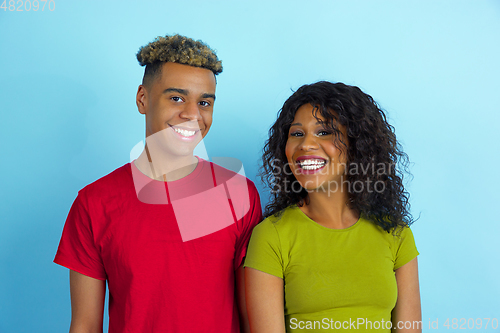 Image of Young emotional african-american man and woman on blue background