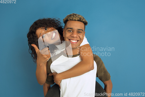 Image of Young emotional african-american man and woman on blue background