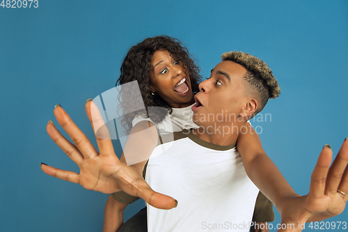 Image of Young emotional african-american man and woman on blue background