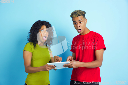 Image of Young emotional african-american man and woman on blue background
