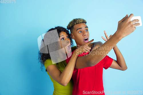 Image of Young emotional african-american man and woman on blue background