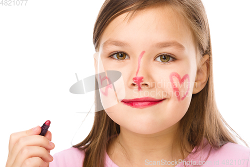 Image of Little girl is applying lipstick on her cheek