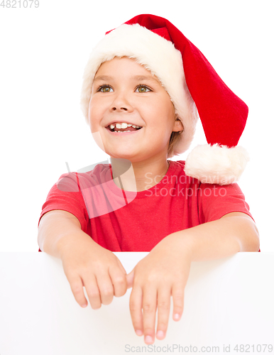 Image of Little girl in santa hat is holding blank board