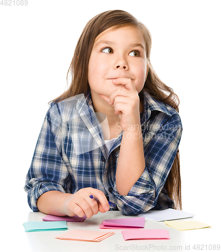 Image of Girl is writing on color stickers using pen