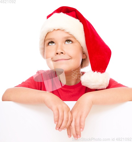 Image of Little girl in santa hat is holding blank board