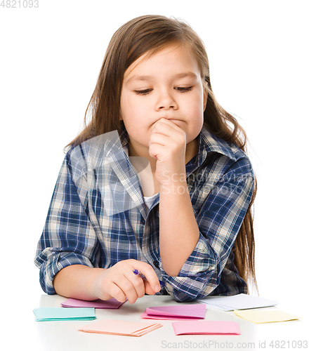 Image of Girl is writing on color stickers using pen