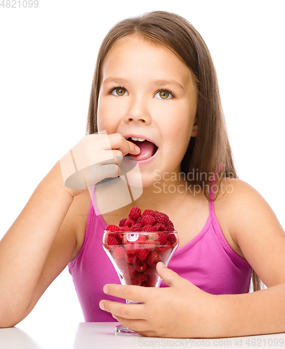 Image of Happy little girl is eating raspberries