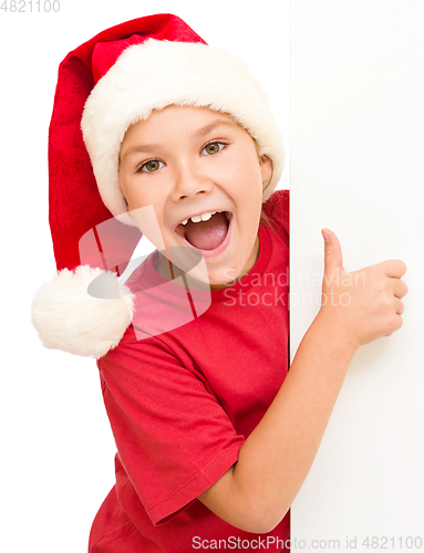 Image of Little girl in santa hat is holding blank board