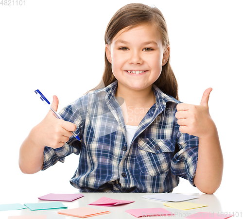 Image of Girl is writing on color stickers using pen