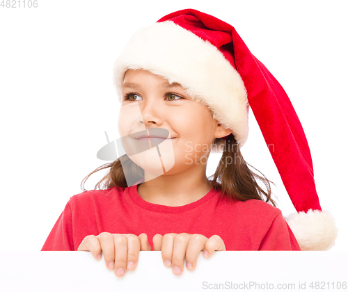 Image of Little girl in santa hat is holding blank board