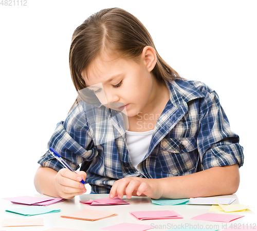 Image of Girl is writing on color stickers using pen