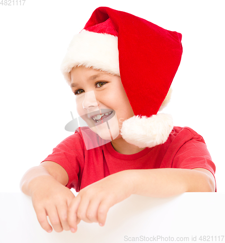 Image of Little girl in santa hat is holding blank board