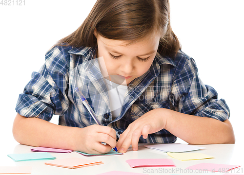 Image of Girl is writing on color stickers using pen