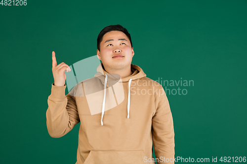 Image of Asian man\'s portrait isolated over green studio background with copyspace