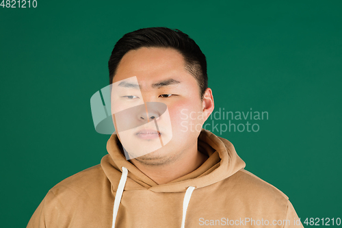 Image of Asian man\'s portrait isolated over green studio background with copyspace