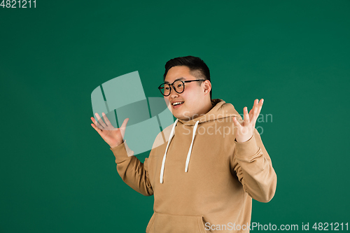Image of Asian man\'s portrait isolated over green studio background with copyspace
