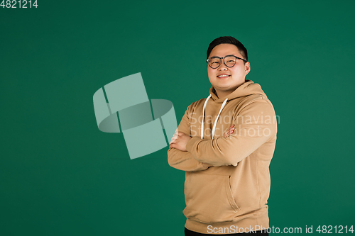 Image of Asian man\'s portrait isolated over green studio background with copyspace