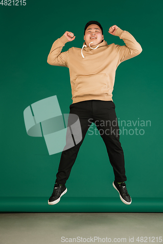 Image of Asian man\'s portrait isolated over green studio background with copyspace