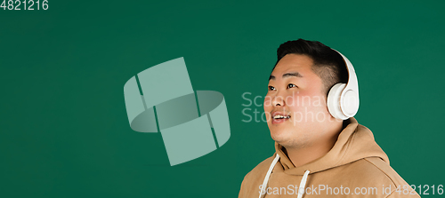 Image of Asian man\'s portrait isolated over green studio background with copyspace