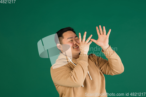 Image of Asian man\'s portrait isolated over green studio background with copyspace