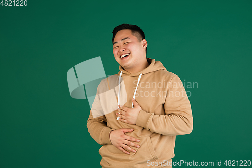 Image of Asian man\'s portrait isolated over green studio background with copyspace