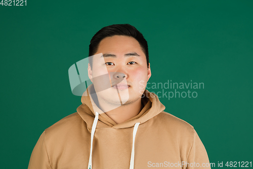 Image of Asian man\'s portrait isolated over green studio background with copyspace