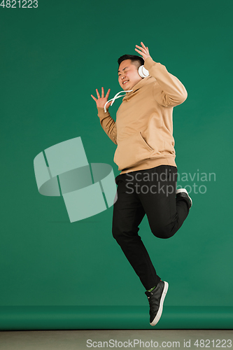 Image of Asian man\'s portrait isolated over green studio background with copyspace