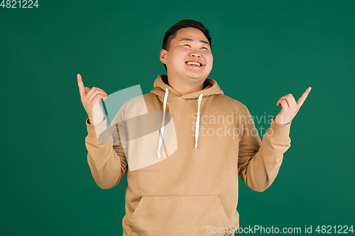 Image of Asian man\'s portrait isolated over green studio background with copyspace