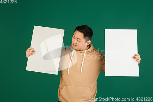 Image of Asian man\'s portrait isolated over green studio background with copyspace